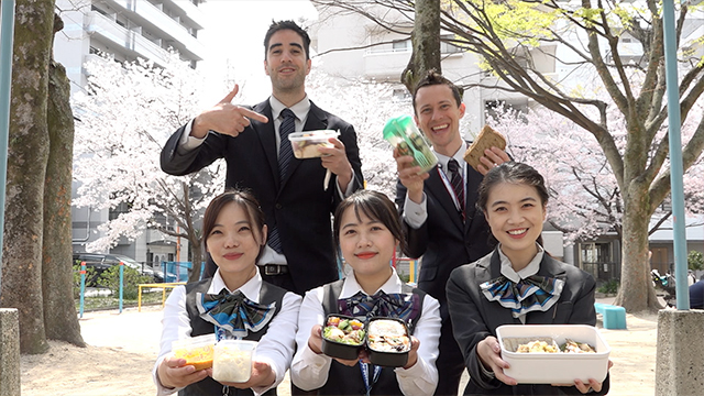 This group of bento makers works at a real estate firm in Hiroshima City, helping foreign residents to find homes. Each of their bentos contains different specialties from home, from Vietnamese fried spring rolls, to Chinese tomato and egg, to Nepalese dumplings, to an American peanut butter and banana sandwich. They enjoy their bentos on a picnic under the cherry blossoms.
